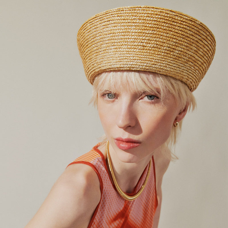 Woman wearing a straw hat with a plain background