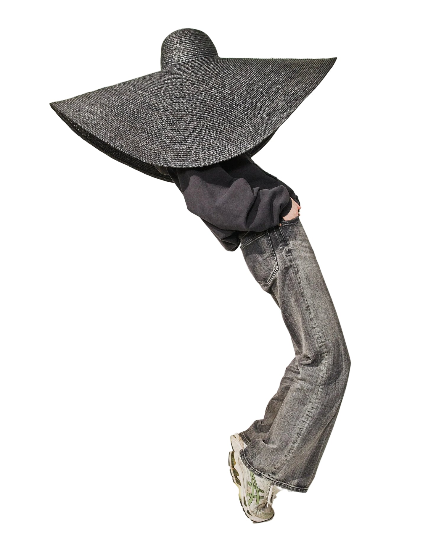 Person wearing a large black straw hat against a white background